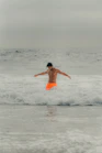 a young boy is jumping in the water at the beach