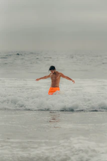a young boy is jumping in the water at the beach