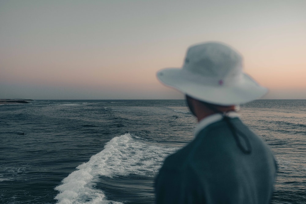 a man in a hat looking out at the ocean