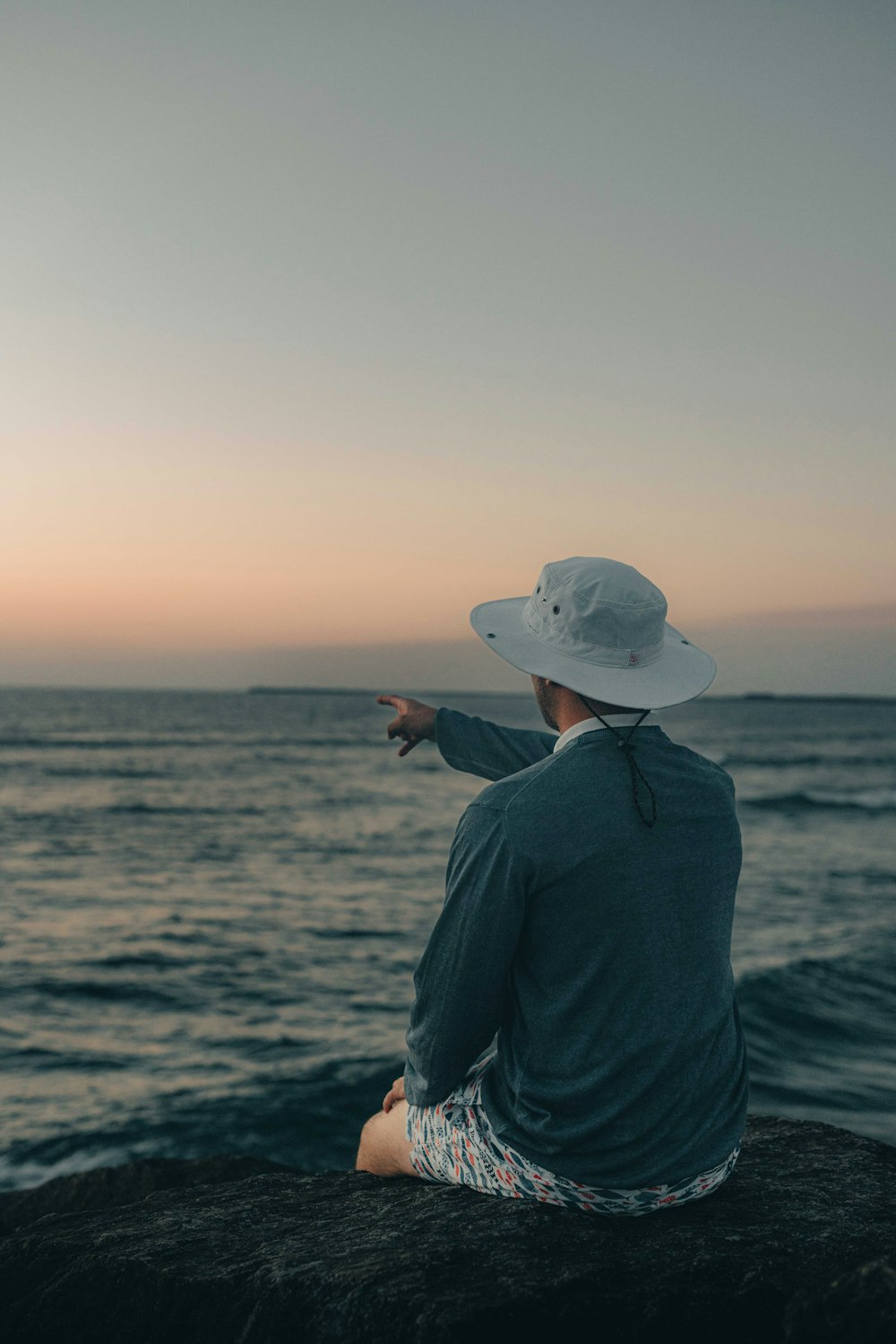 a person sitting on a rock looking out at the ocean