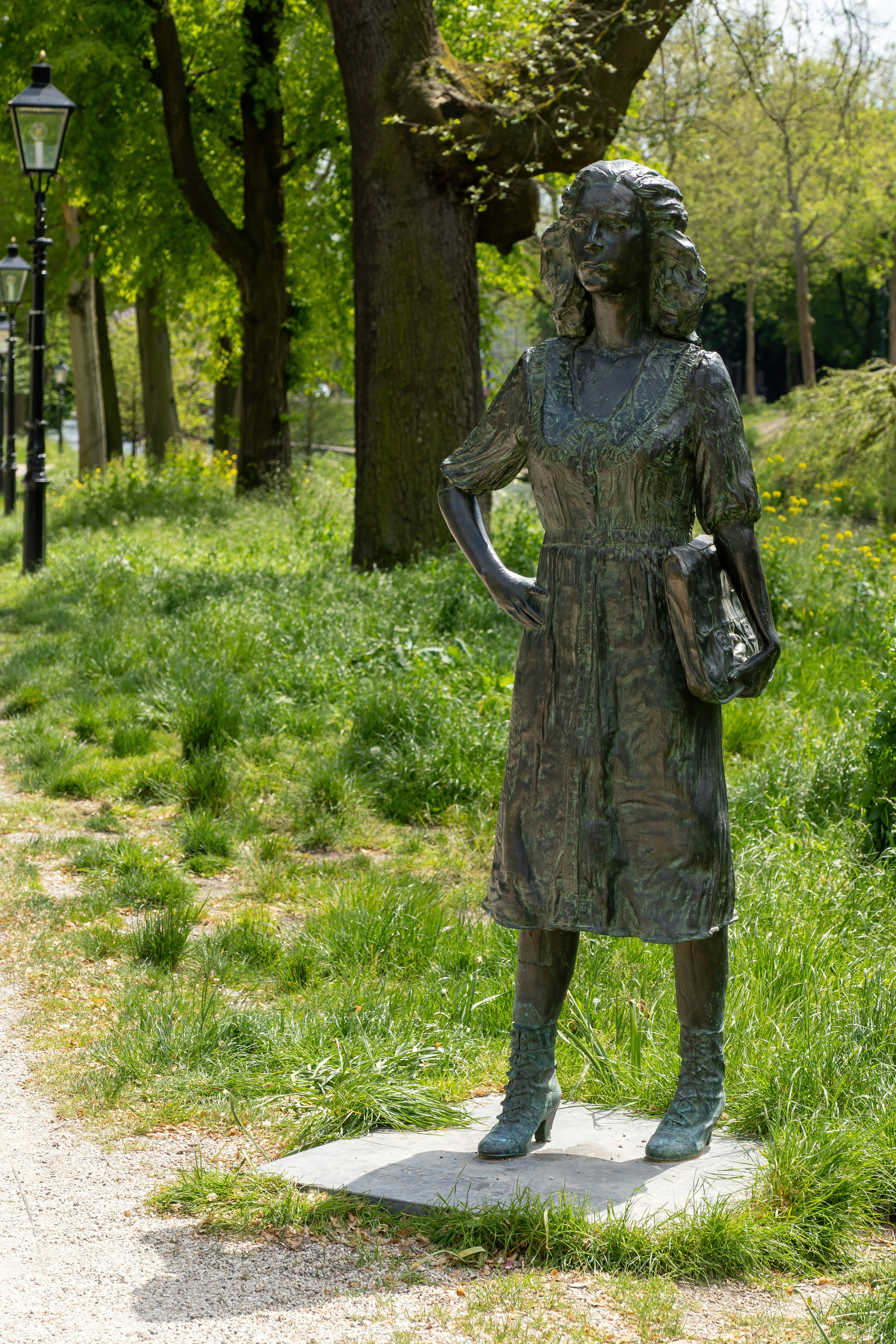 a statue of a woman holding a purse in a park