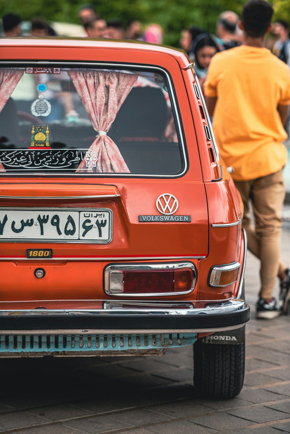 a small orange car parked in front of a crowd of people