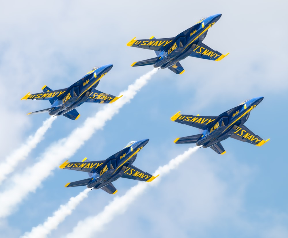 four blue and yellow jets flying in formation