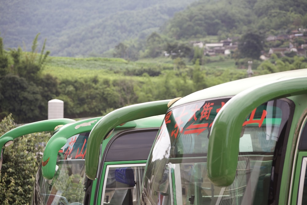 a row of green buses parked next to each other