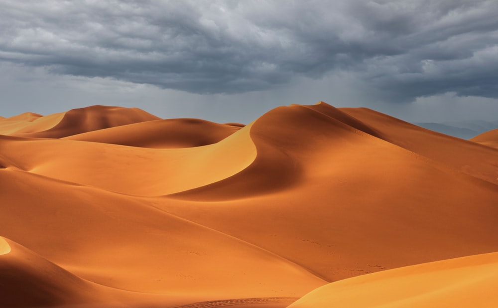 a large group of sand dunes under a cloudy sky