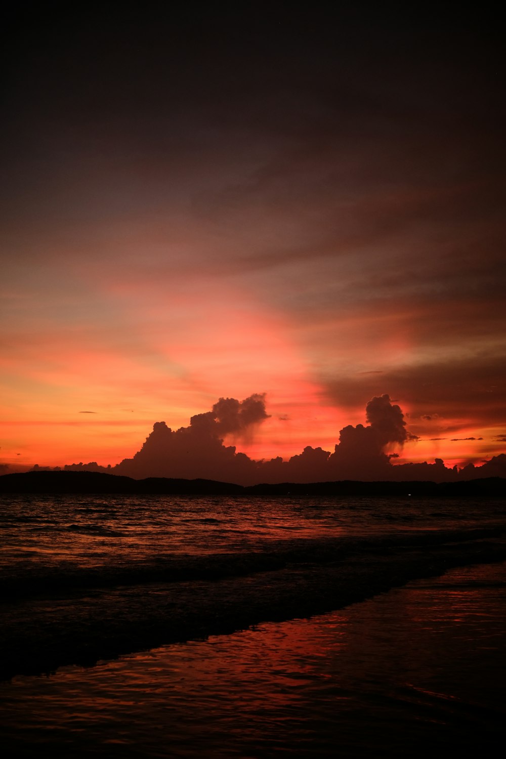 the sun is setting over the water at the beach