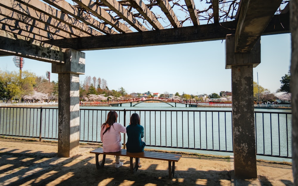 a couple of women sitting on top of a wooden bench