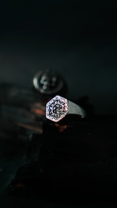Elegant modern ring with engraved spiritual motifs resting on a smooth dark surface.