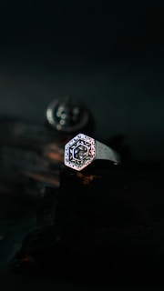 Close-up of a sleek silver ring on a dark textured background, highlighting its minimalist design
