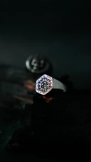 Close-up of a handcrafted silver ring with intricate celestial engravings against a dark background.