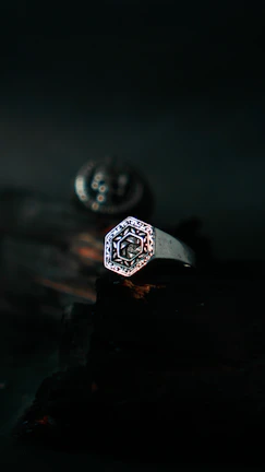 Close-up of a delicate silver ring with intricate celestial engravings on a dark velvet background.