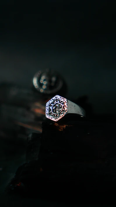 Close-up of a handcrafted silver ring with intricate celestial engravings against a dark background.