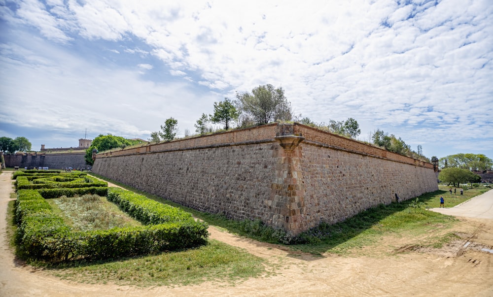 a stone wall surrounded by hedges in a park