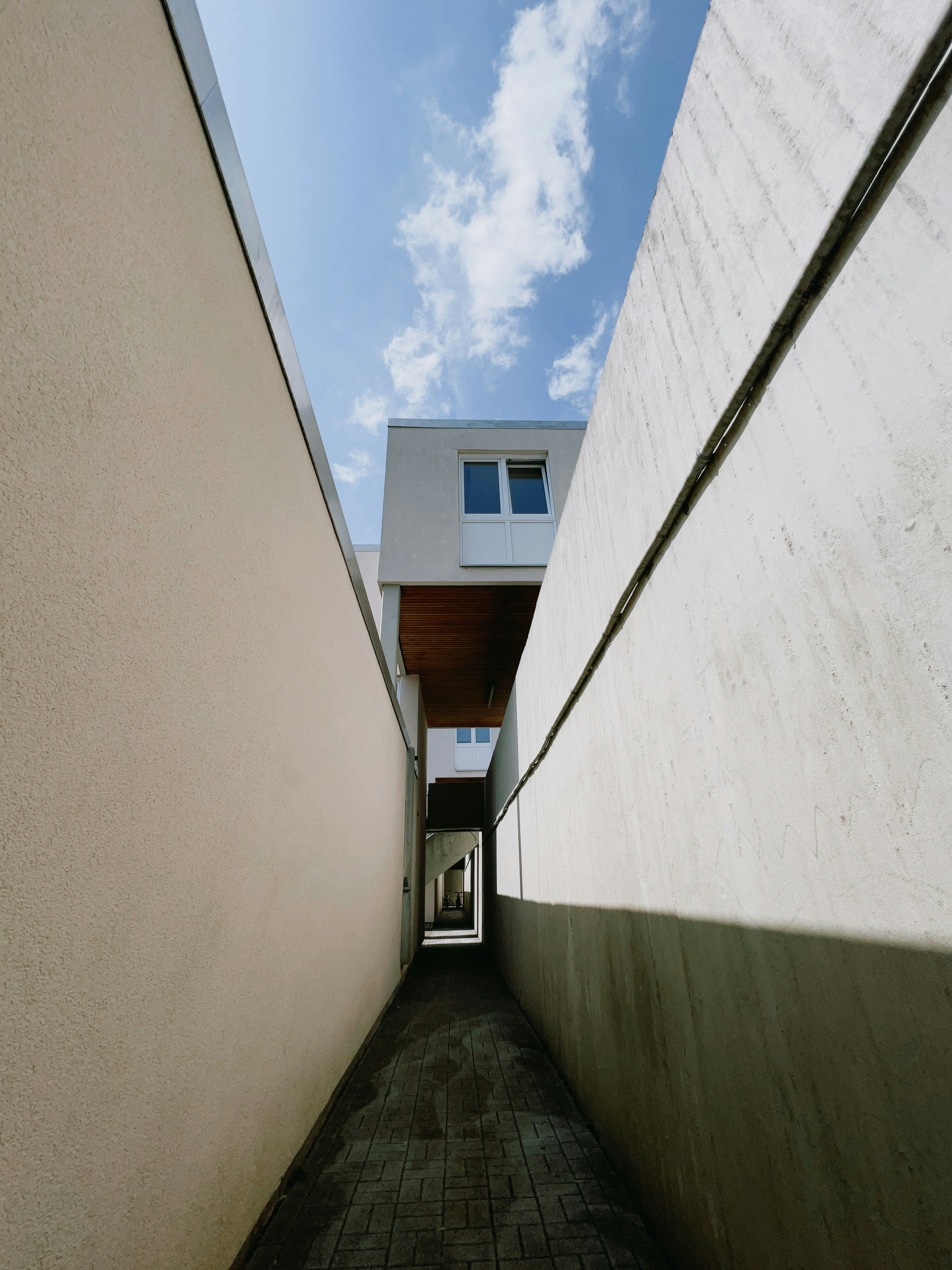 ein schmaler Gehweg zwischen zwei Gebäuden mit Himmelshintergrund