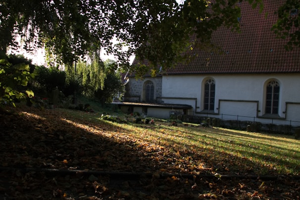A warm, sunlit view of St. Thomas Syriac Orthodox Church surrounded by peaceful greenery.