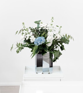 A modern metal flower table stand showcasing a minimalist bouquet in a bright, airy room.