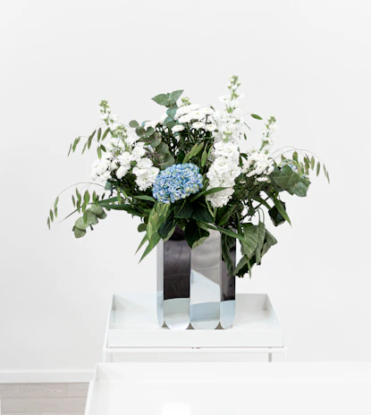 Minimalist table flower arrangement in a sleek glass vase, blending midnight blue and champagne gold tones.