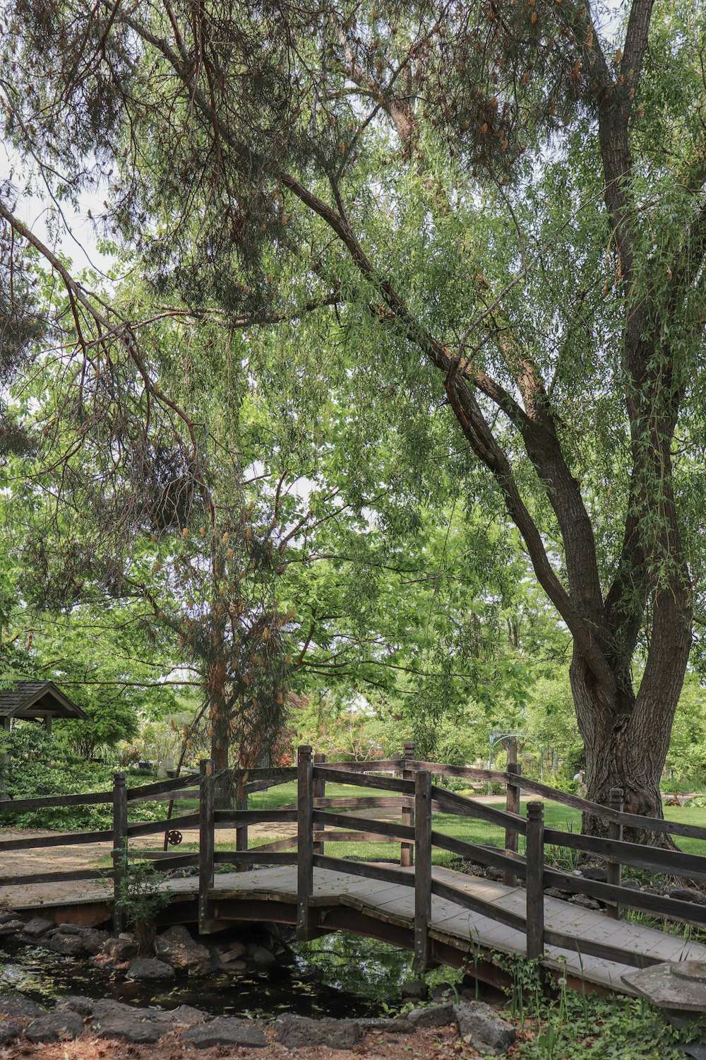 a wooden bridge over a small pond in a park