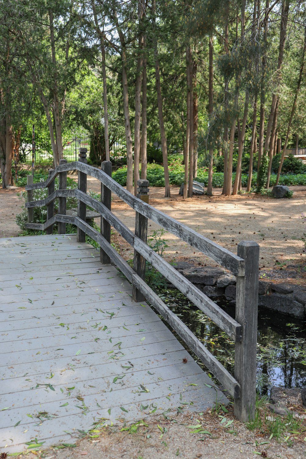 a wooden bridge over a small pond in a park