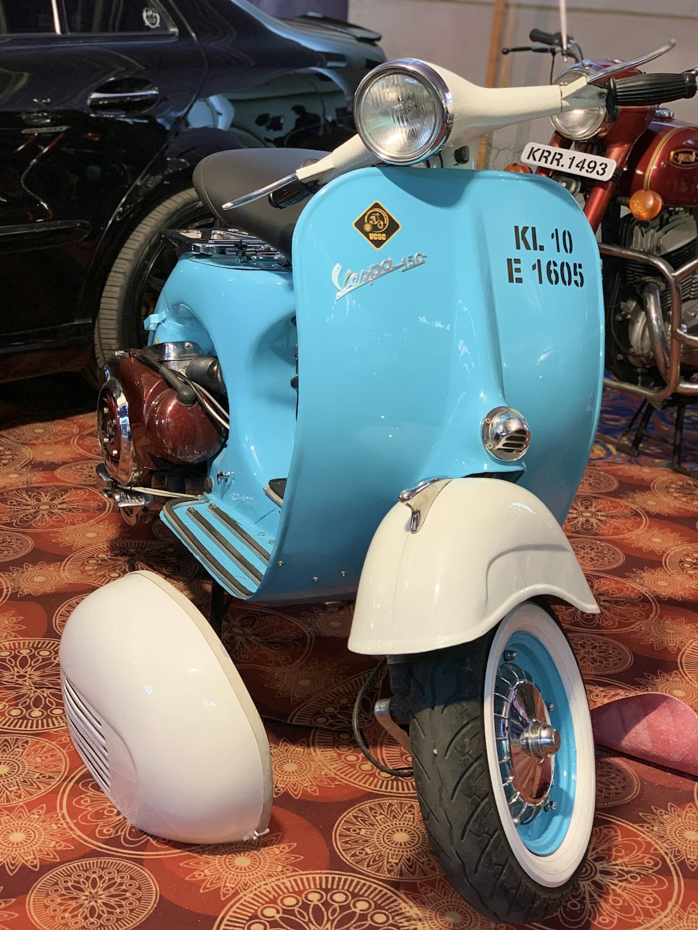 a blue and white motor scooter sitting on top of a carpet