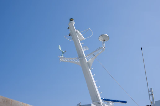A technician carefully installing a maritime VSAT antenna on a ship's deck under a clear blue sky.