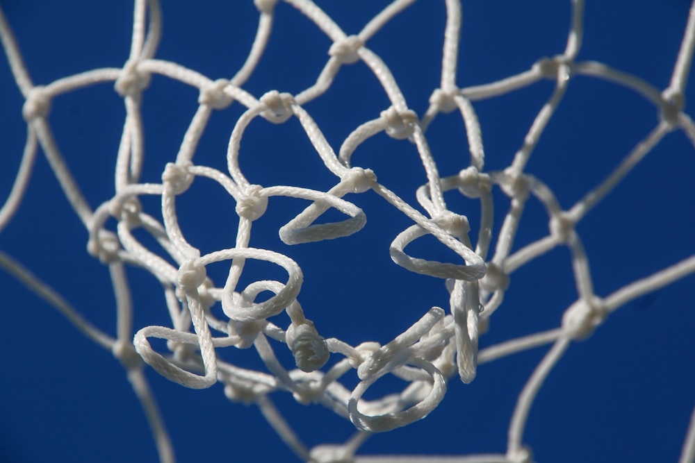 a close up of a basketball net with a blue sky in the background