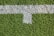 A patch of artificial grass with a thick white line running horizontally across it, intersected by a shorter vertical white line.