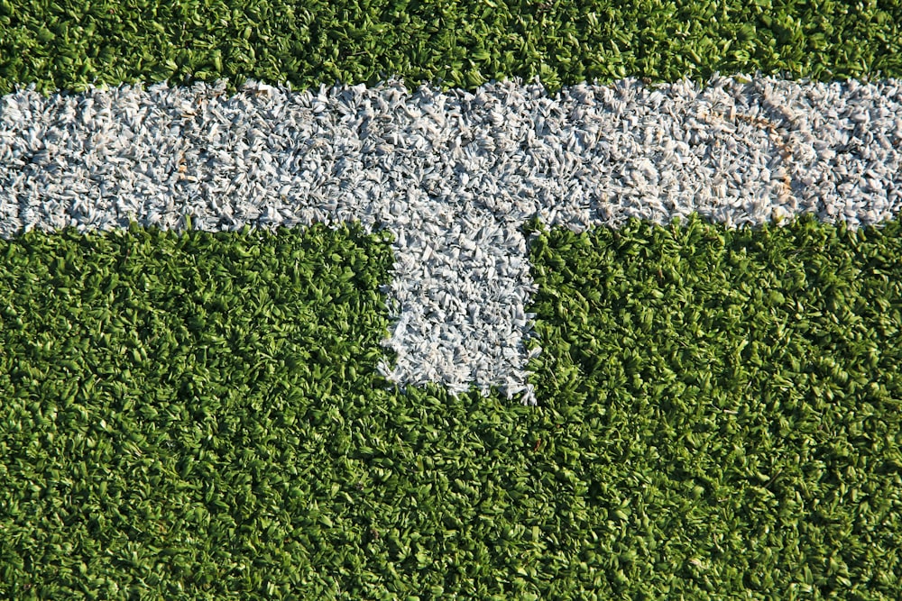 a green grass field with a white arrow painted on it
