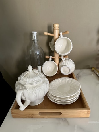 A serene wooden tea tray with a steaming porcelain teapot and delicate tea cups arranged neatly on a bamboo mat.