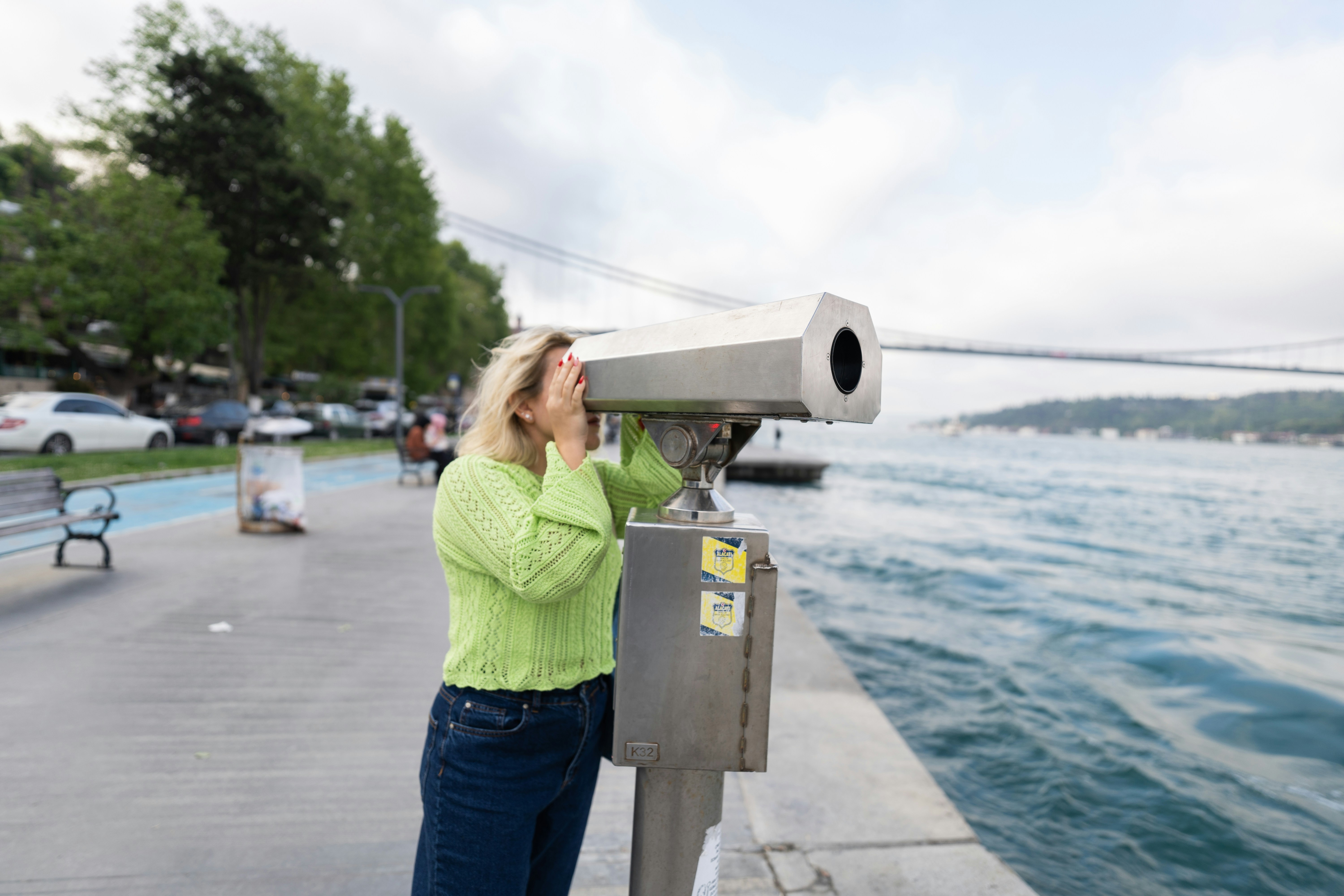 a woman looking through a telescope at the water, 