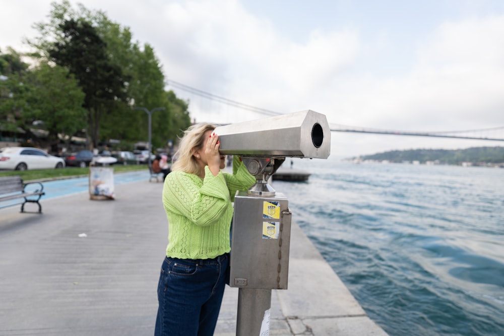 Una mujer mirando a través de un telescopio el agua