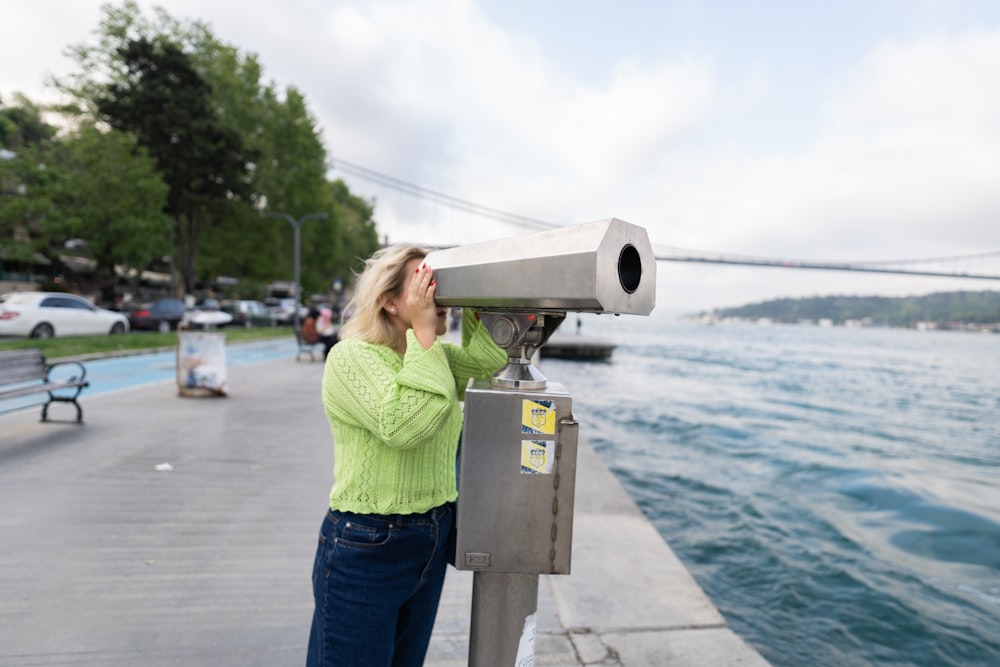 a woman looking through a telescope at the water