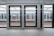 Glass platform doors at a train station with visible tracks and another platform on the opposite side. The modern structure includes metal framing and clear panels, providing a view of the train tracks and reflections of station surroundings.