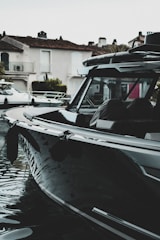 A sleek, modern boat anchored in calm waters with a scenic backdrop of trees.