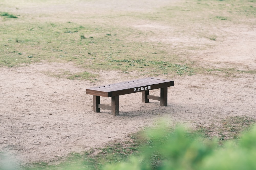 a wooden bench sitting on top of a dirt field