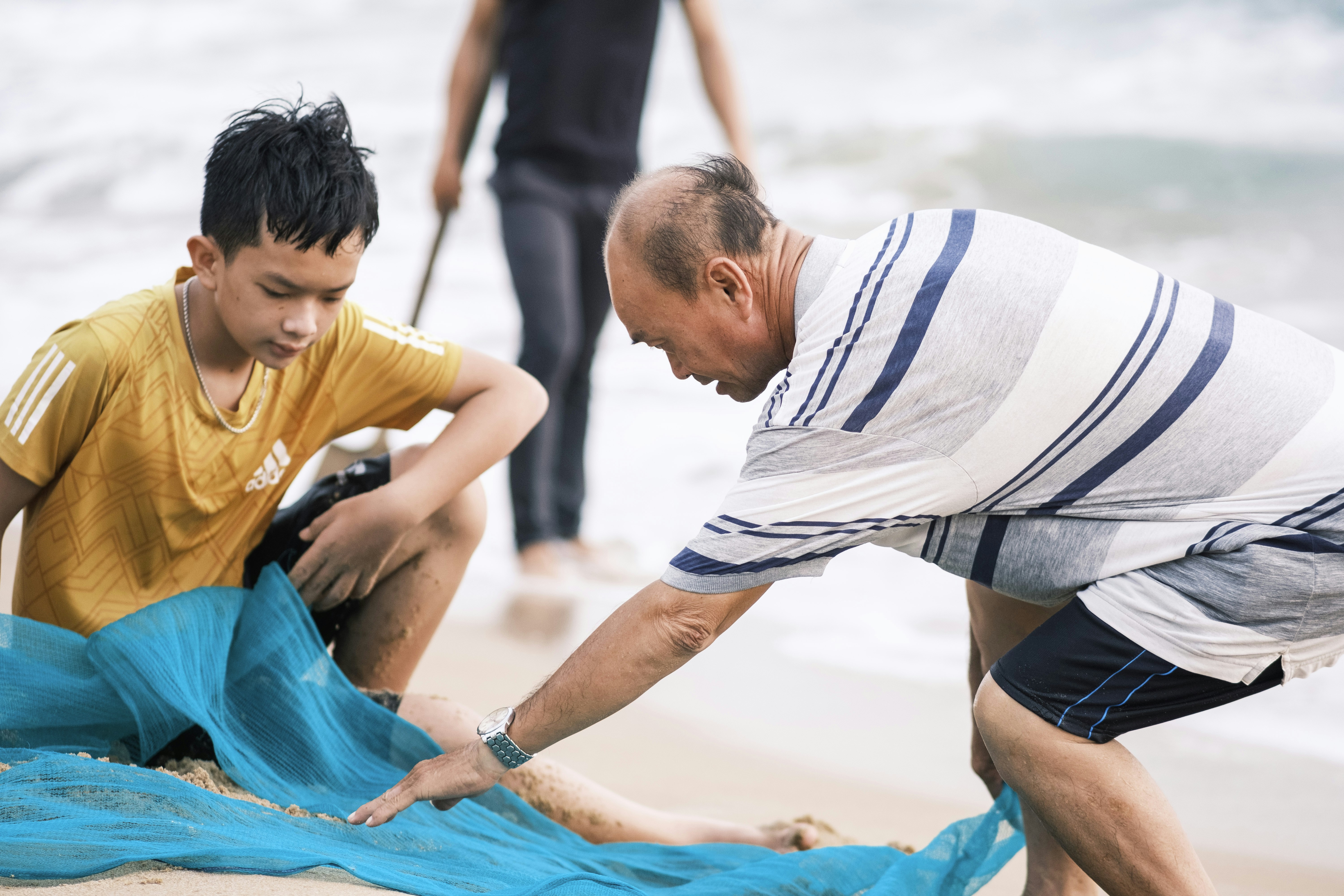 青い布を着た浜辺の男と少年