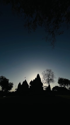A serene North Indian-style temple silhouette at sunset with glowing diyas in the foreground.