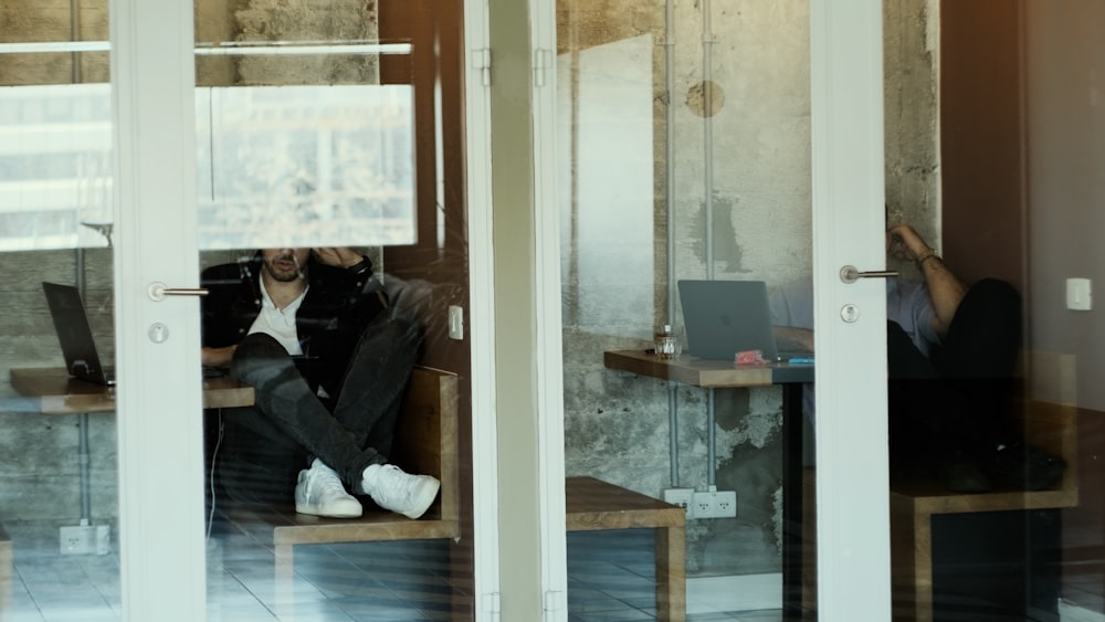 a man sitting on a bench in front of a laptop computer