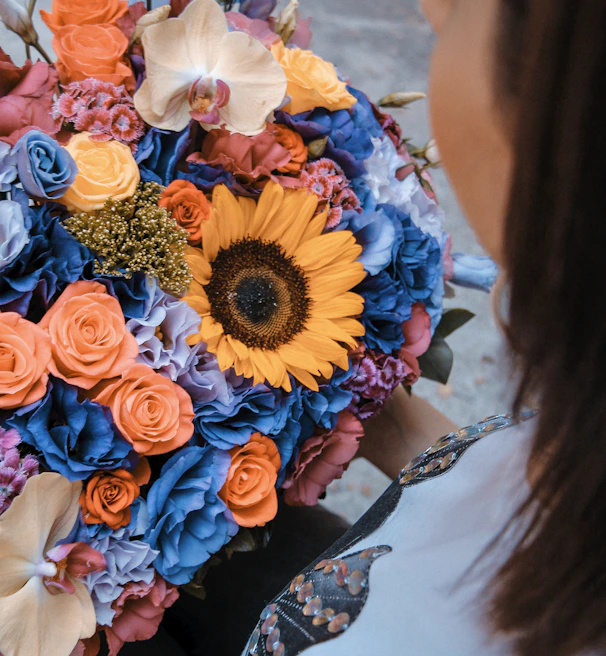 A large, vibrant bouquet of roses being presented to a delighted recipient outdoors.