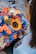 A happy customer holding a colorful flower arrangement outside on a sunny day.