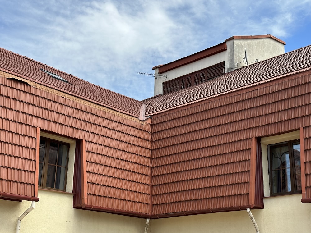 a red roof with two windows and a sky background