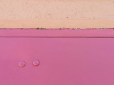 a close up of a pink cabinet with two knobs