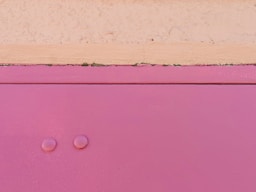 a close up of a pink cabinet with two knobs