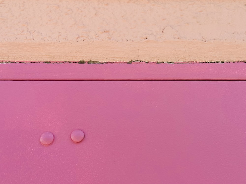 a close up of a pink cabinet with two knobs