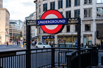 A busy London Underground station entrance with commuters and iconic roundel signs.
