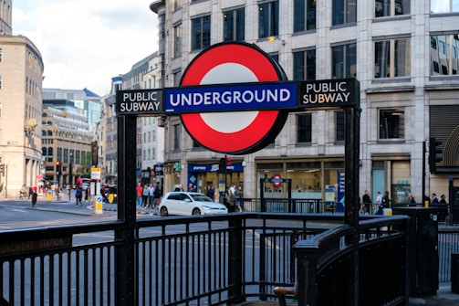 A busy London Underground station entrance with commuters and iconic roundel signs.