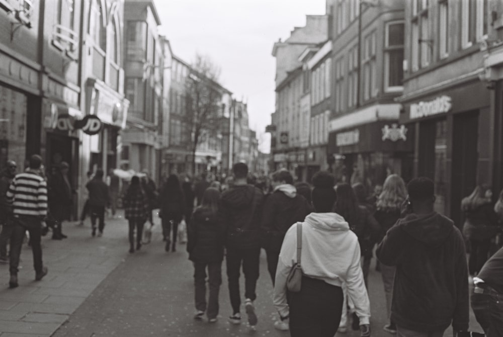 a group of people walking down a street next to tall buildings