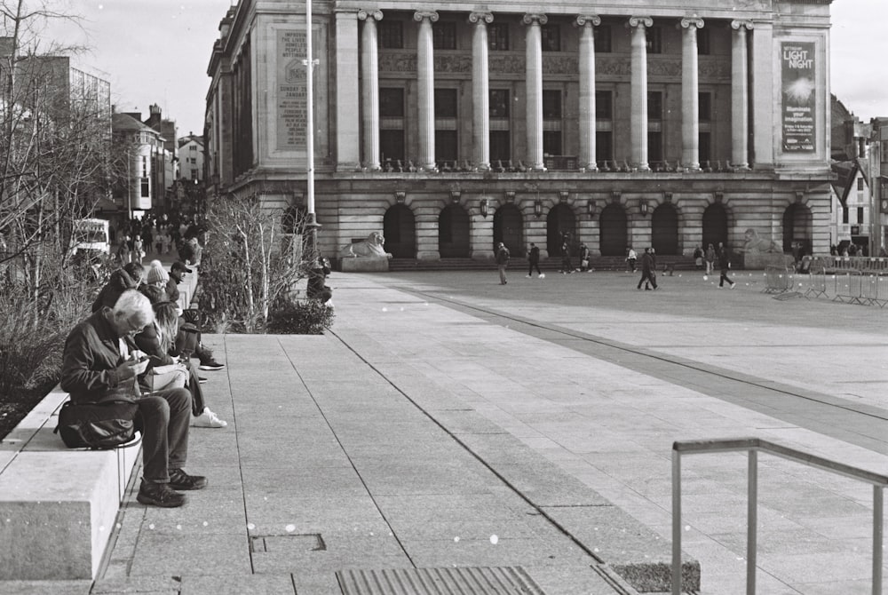 a black and white photo of people sitting on a bench