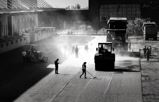 Photo of a freshly paved highway with construction workers and machinery in action.