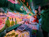 Photographer capturing a food market vendor arranging colorful fruits.